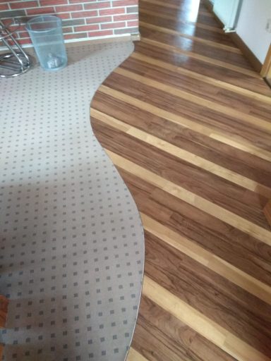 Teppich mit geschwungener Kante auf Holzboden mit schmalen Holzleisten.